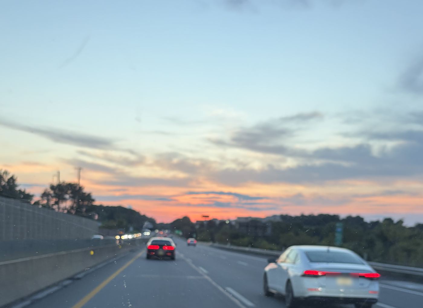 Highway traffic at sunset under a pink and blue sky