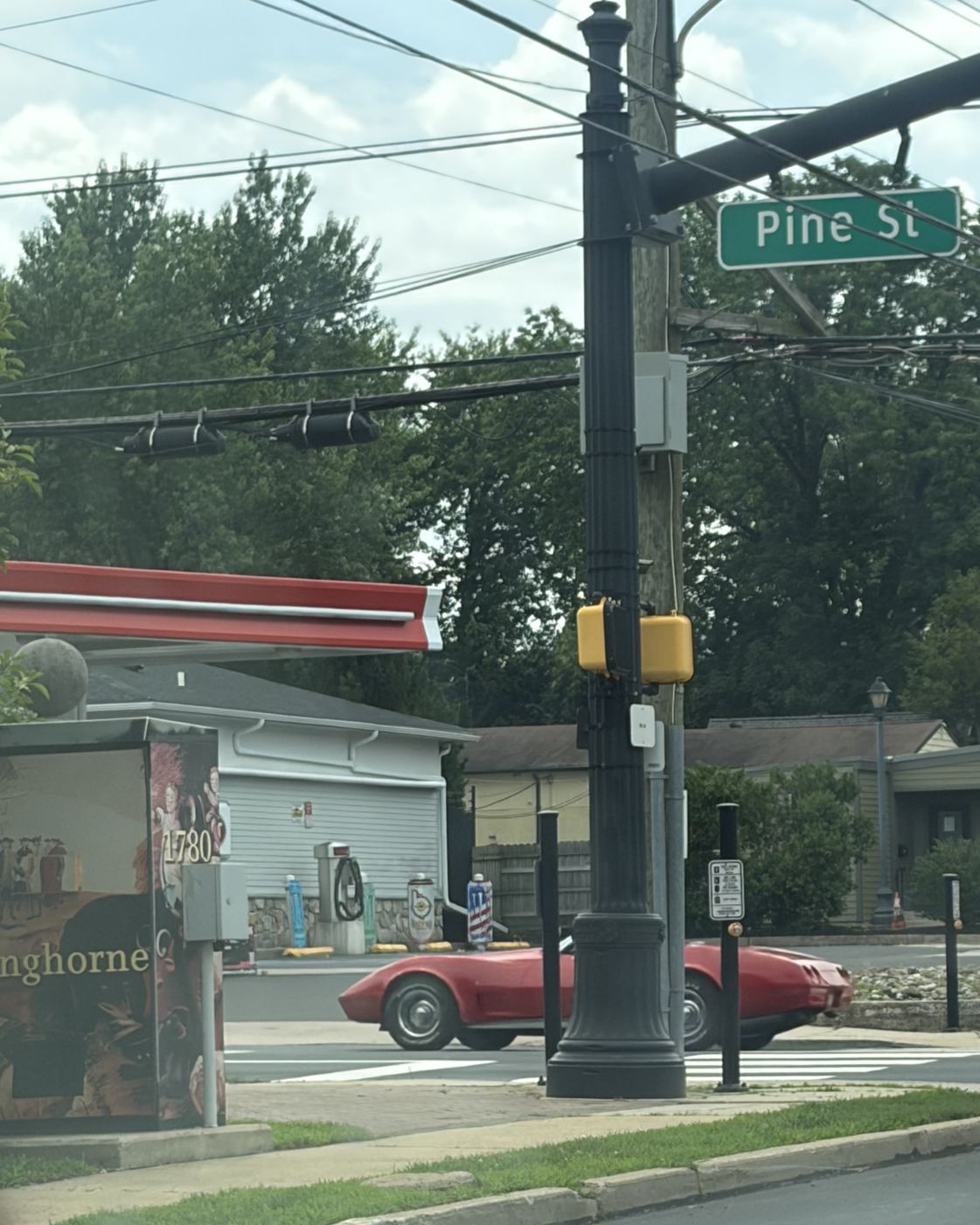 Pine Street intersection in Langhorne Borough, with a painted Langhorne 1780 utility box, a lamppost and a red classic car passing